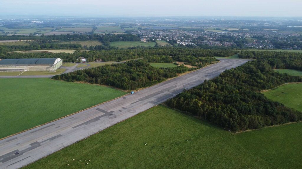 An aerial view of an old runway and aircraft hangar in the English countryside.